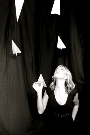 Courtney Dashe looking up at hanging paper airplanes