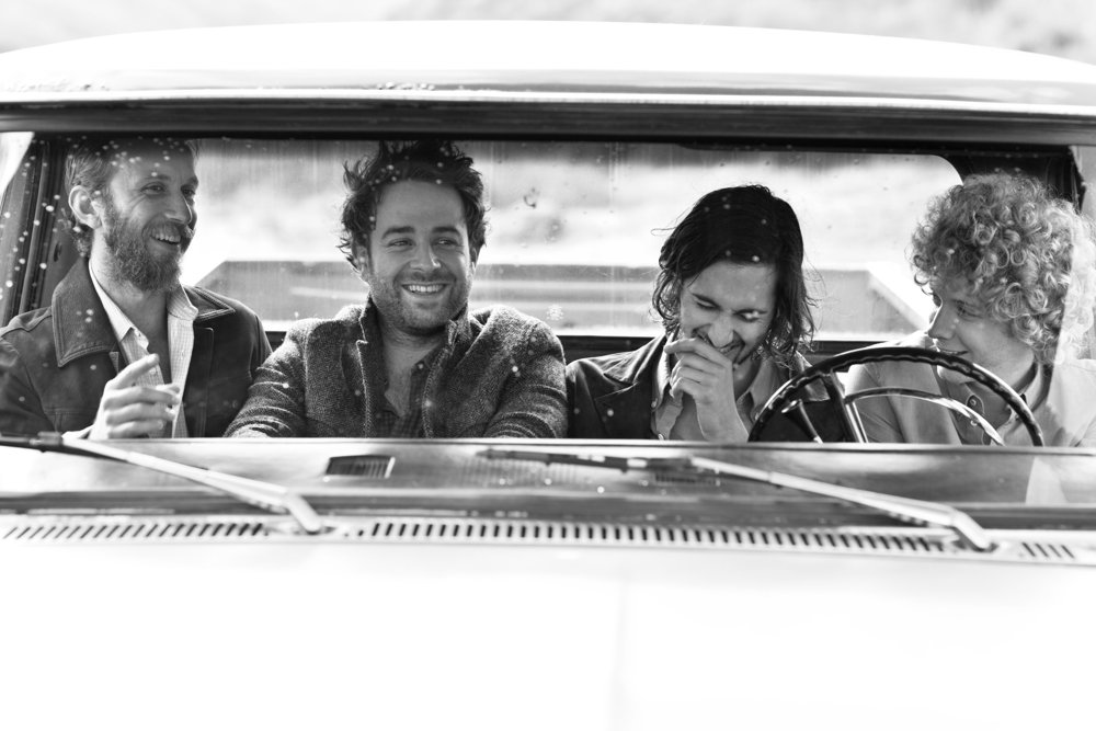 The four members of Dawes laughing in the cab of an old truck