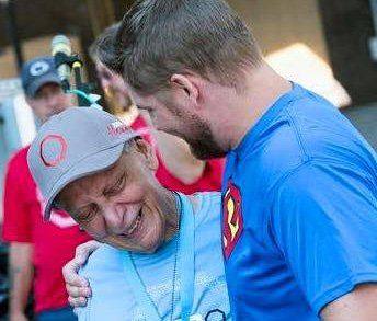 Jimmy Charles in a Superman T-shirt embracing an older man in a cap at a Zero Cancer event