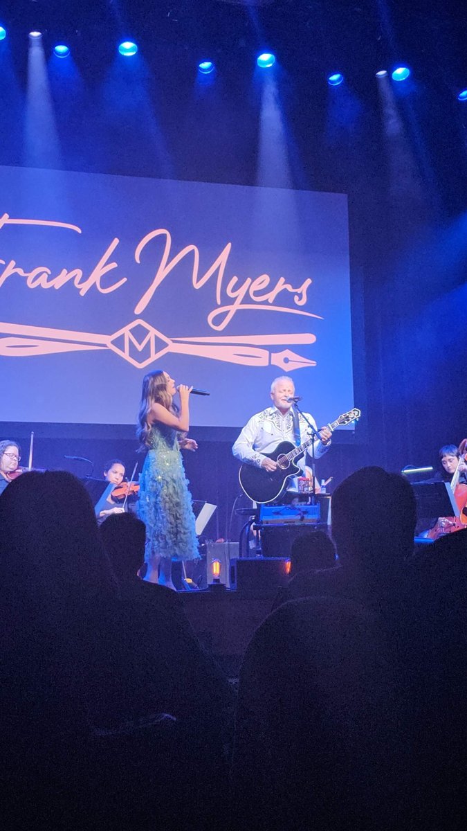 Lauren Mascitti in a sea-green gown sings beside Frank Myers on guitar