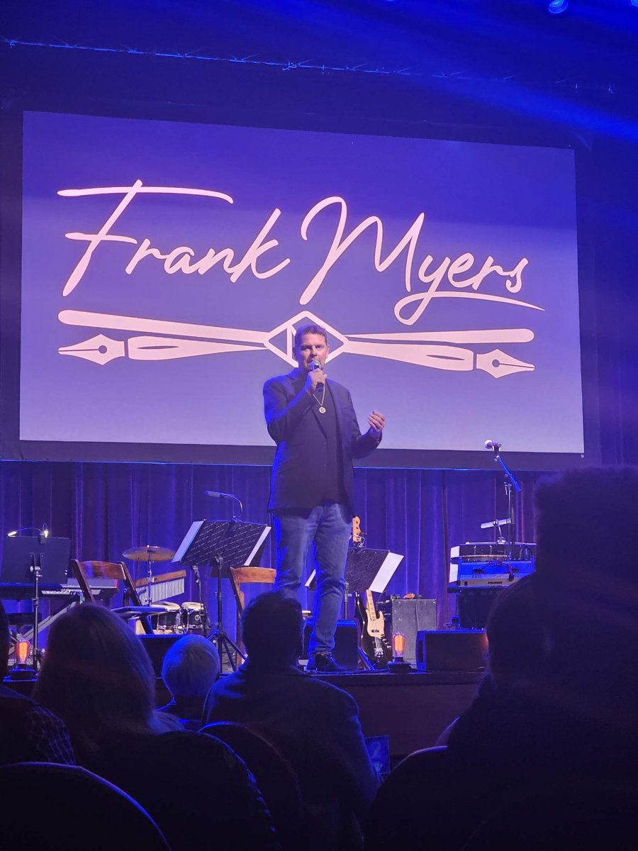 Storme Warren speaks into a microphone in front of the Frank Myers logo