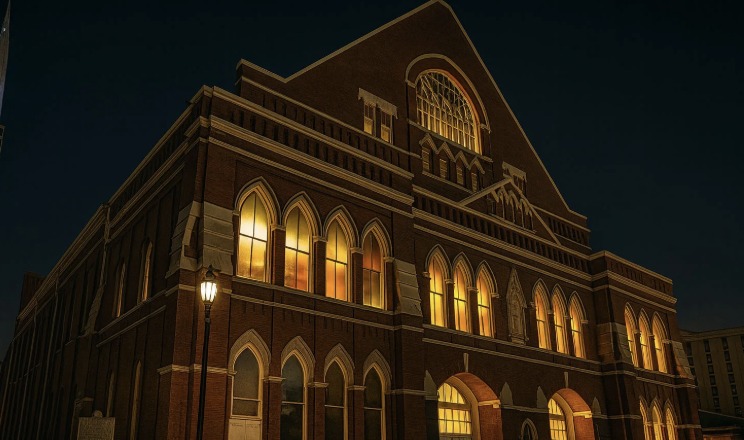 The Ryman Auditorium at night, its arched windows glowing gold